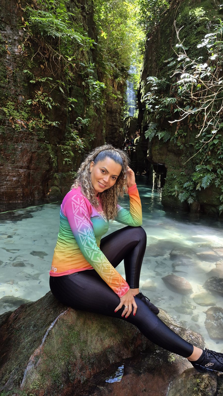 Kelly, da Tribo Go Trip, vestindo a coleção em uma cachoeira